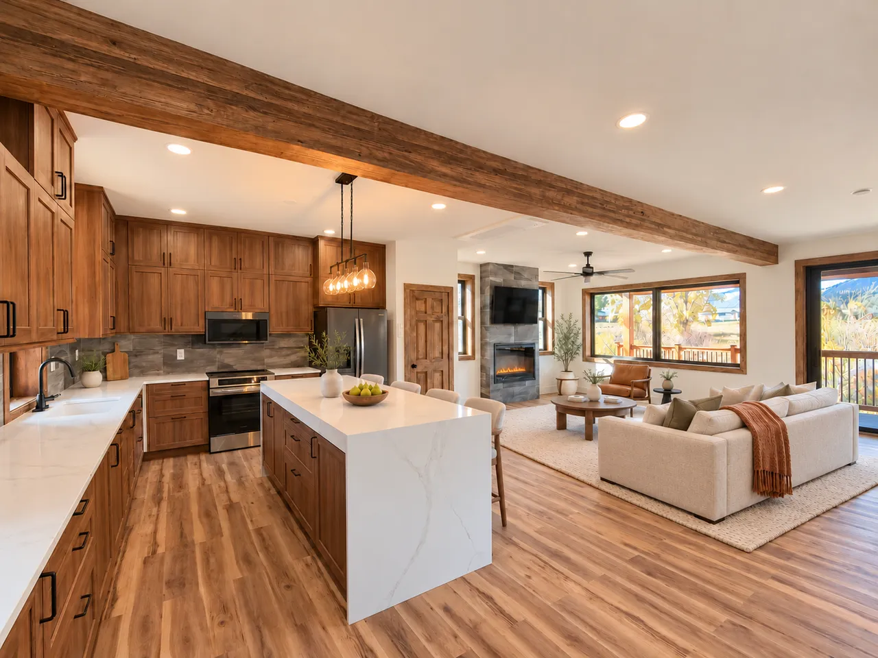 Staged kitchen with waterfall island and induction range, opening to the fireplace and river-facing windows
